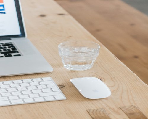 A clean workspace featuring a large water glass alongside a laptop, highlighting daily hydration habits